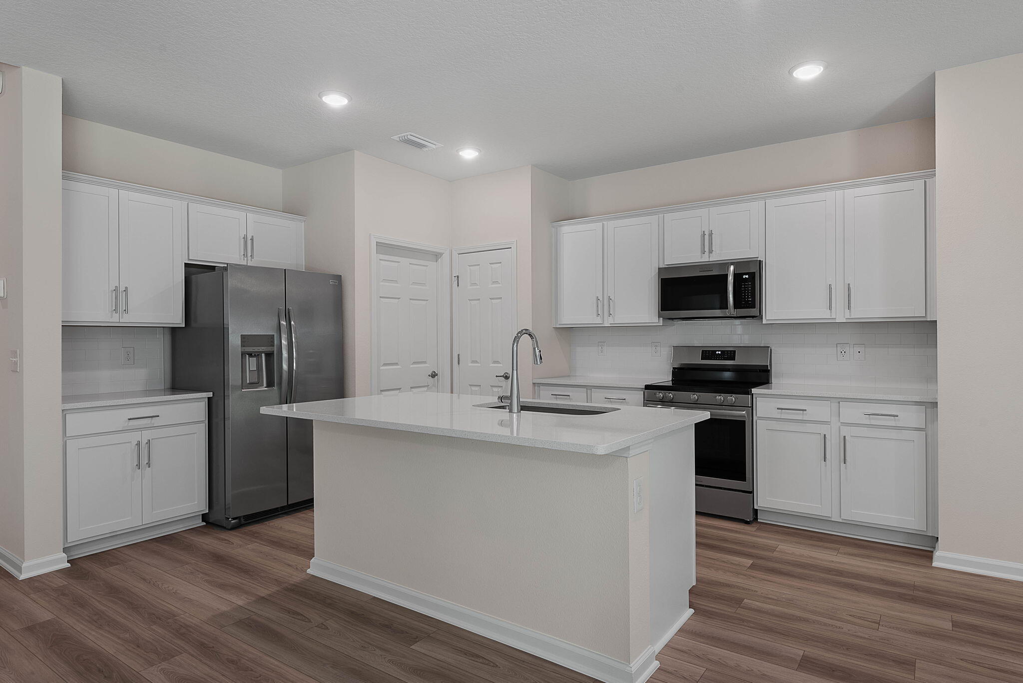 46 Poplar Drive Palm Coast, FL 32164 - Photo 17 of 59 a kitchen with stainless steel appliances a sink stove refrigerator and white cabinets with wooden floor