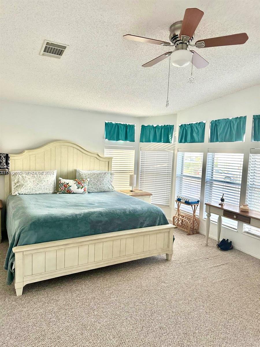 72 Ocean Drive Key Largo, FL 33037 - Photo 12 of 36 a bedroom with a bed a chandelier and large window