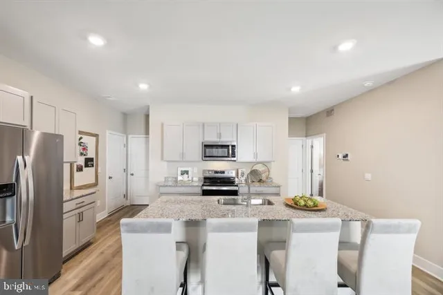 a kitchen with kitchen island a refrigerator stove and white cabinets