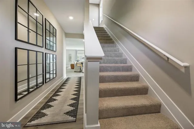 a view of staircase with lots of frames on wall and windows