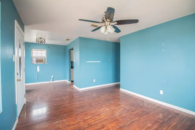 a view of a room with a ceiling fan and hardwood floor