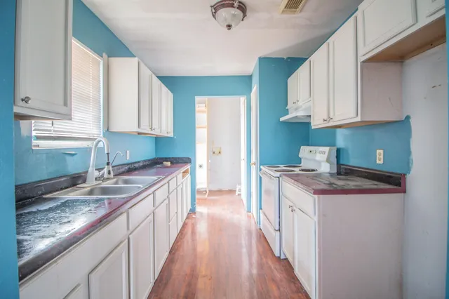 a kitchen with granite countertop a sink stove and cabinets