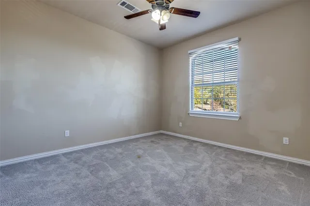 an empty room with a window and a chandelier fan