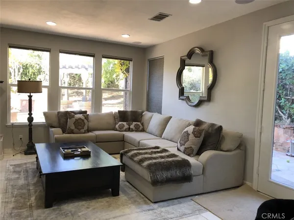 a living room with furniture and a large mirror next to a window