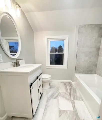 a bathroom with a sink and mirror with bathtub