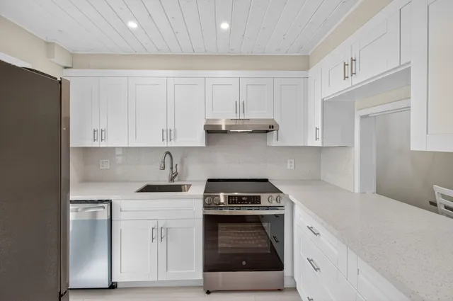 a kitchen with white cabinets and appliances