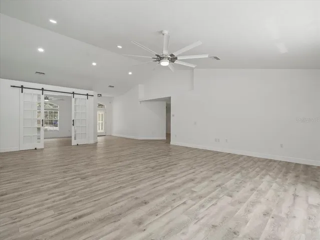 an empty room with wooden floor fan and windows