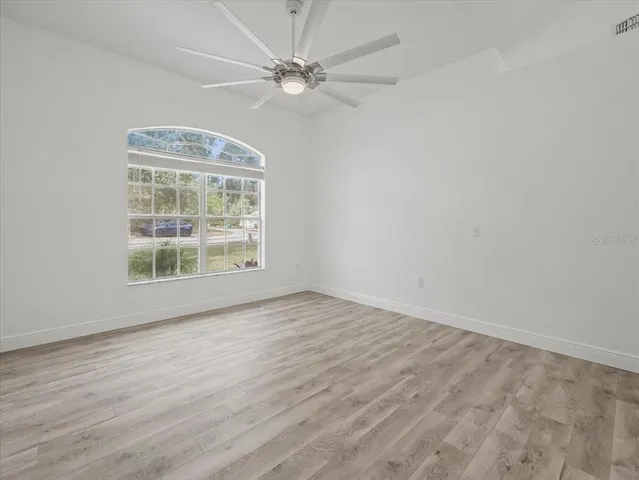 a view of kitchen and empty room with wooden floor