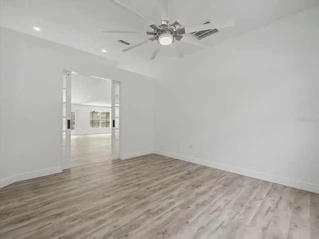 a view of empty room with wooden floor and fan