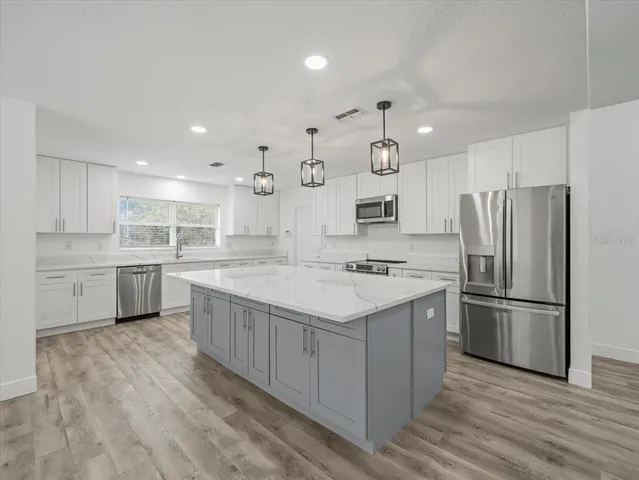 a kitchen with stainless steel appliances white cabinets and a stove top oven