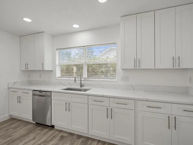 a view of an empty room with wooden floor and a ceiling fan