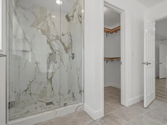 an empty room with wooden floor chandelier fan and windows