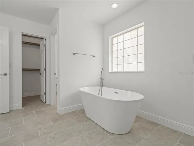 a view of an empty room with wooden floor and fan