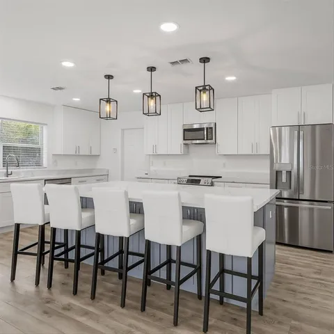 a kitchen with stainless steel appliances a table chairs microwave and cabinets