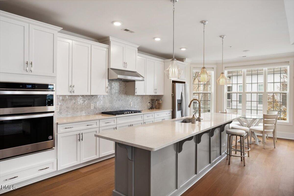 10530 Sablewood Drive, Unit 215 Raleigh, NC 27617 - Photo 11 of 40 a kitchen with kitchen island granite countertop a stove a sink a center island and wooden floor