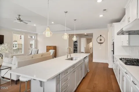a large white kitchen with a large island oven a sink stainless steel appliances and cabinets