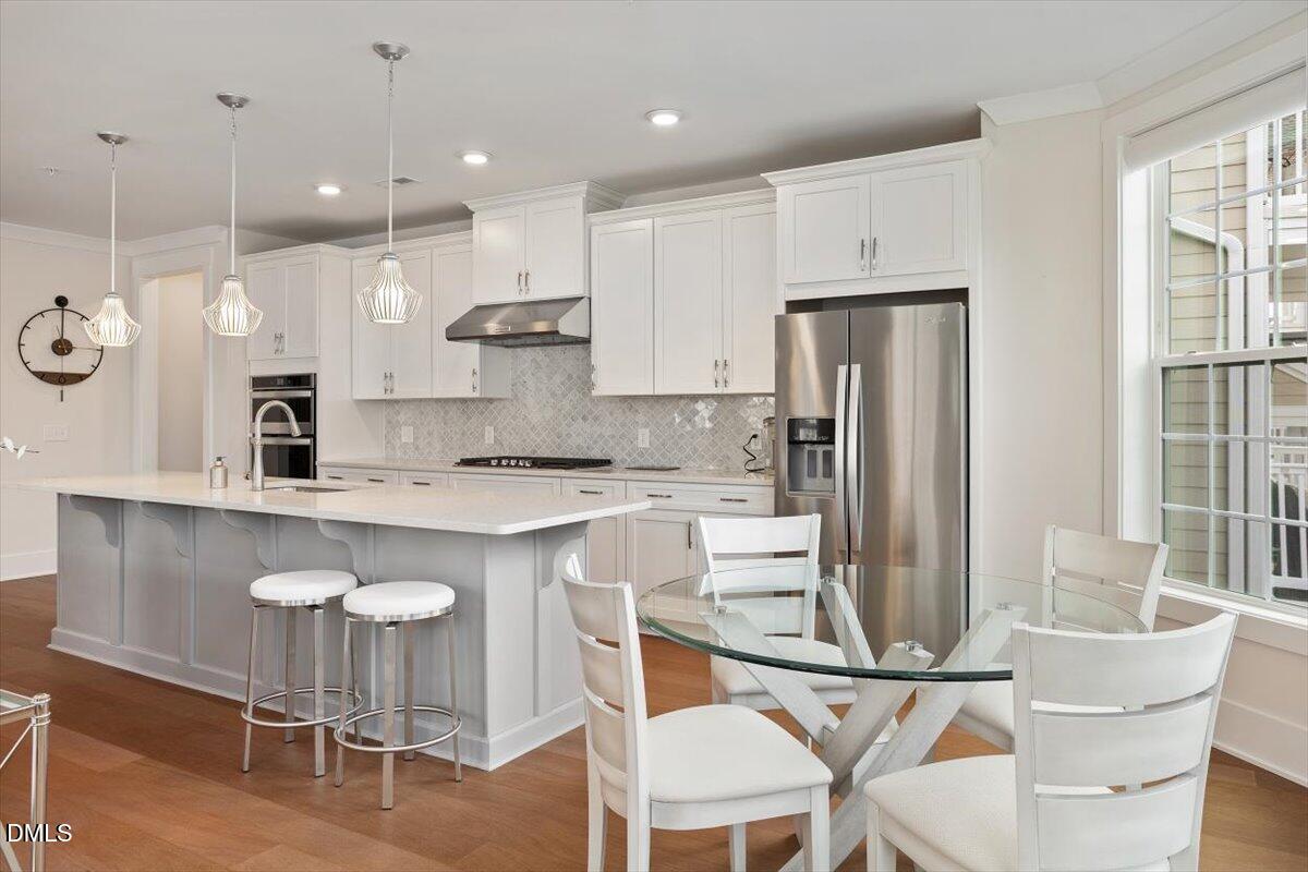 10530 Sablewood Drive, Unit 215 Raleigh, NC 27617 - Photo 18 of 40 a kitchen with kitchen island granite countertop a table chairs refrigerator a sink and a stove
