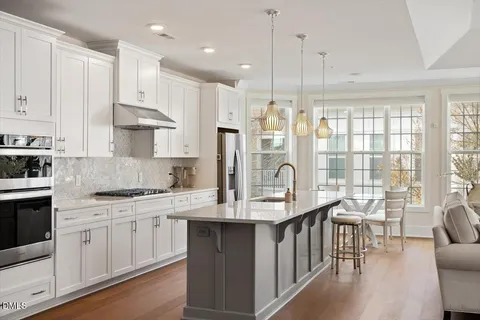 a kitchen with stainless steel appliances granite countertop a stove a sink dishwasher and a refrigerator with wooden floor