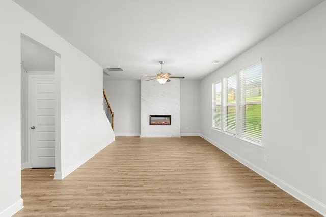 an empty room with wooden floor and ceiling fan