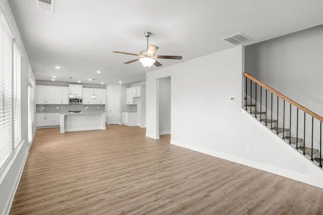 a view of an empty room with a kitchen and wooden floor