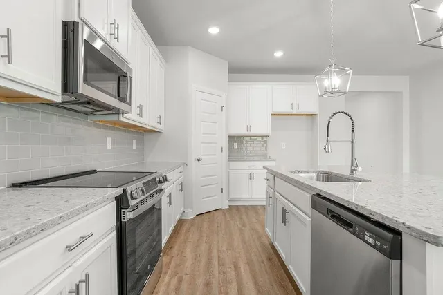 a kitchen with a sink chandelier and wooden floor