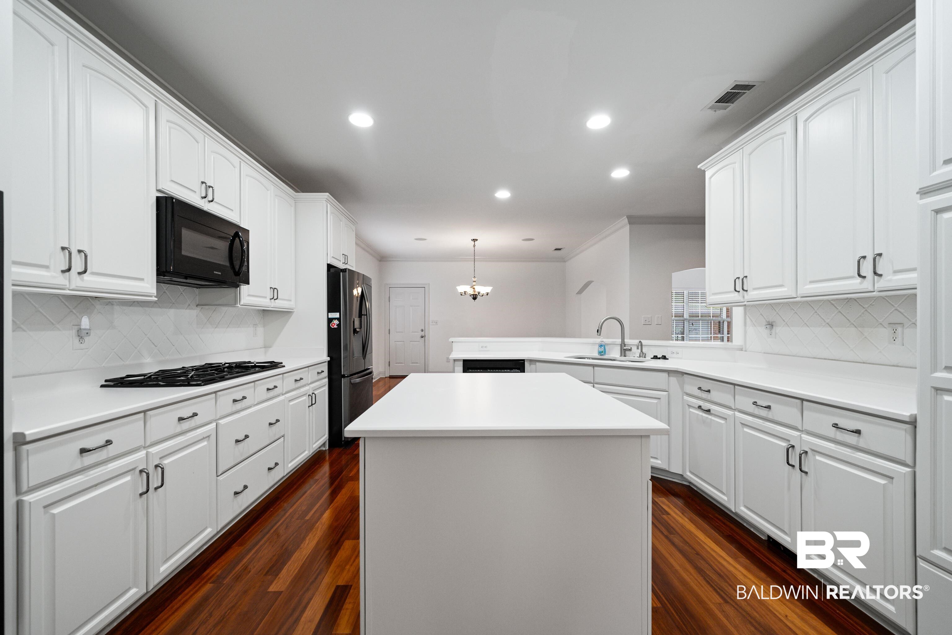 404 Savannah Lane Foley, AL 36535 - Photo 17 of 29 Kitchen featuring a kitchen island, hanging light fixtures, light countertops, black microwave, and a sink