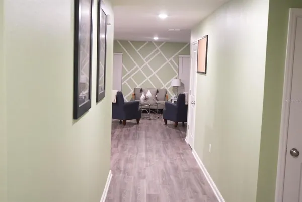 a view of a hallway with wooden floor and a refrigerator