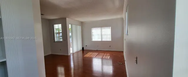 a view of a hallway with wooden floor and a livingroom