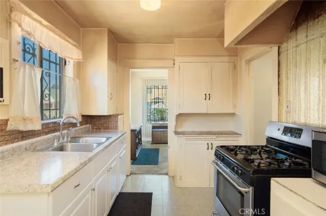 a kitchen with granite countertop a sink stove and cabinets
