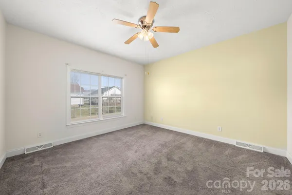 an empty room with a window and a ceiling fan