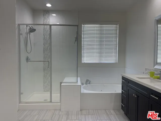 a bathroom with a bathtub a shower a sink and a window