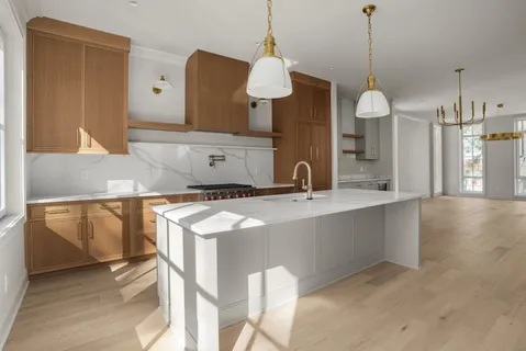 a kitchen with stainless steel appliances kitchen island granite countertop a refrigerator a sink dishwasher a oven with white cabinets and wooden floor