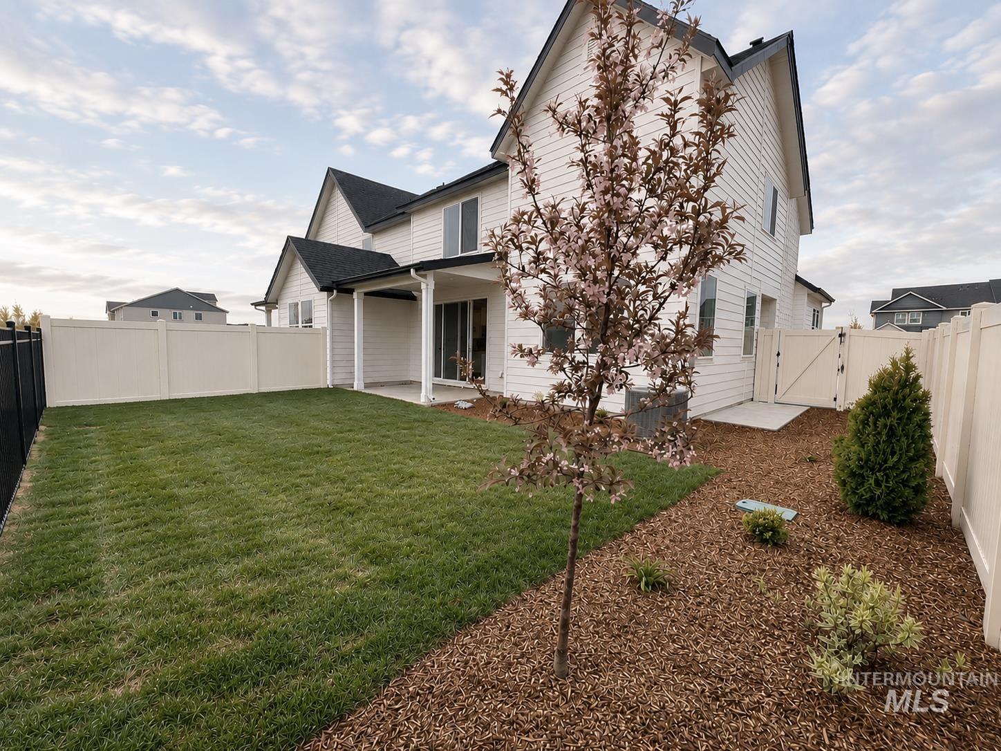 8098 West Fern Street Eagle, ID 83616 - Photo 20 of 22 Expansive backyard featuring a manicured lawn, established landscaping with wood chip ground cover, and a blossoming tree