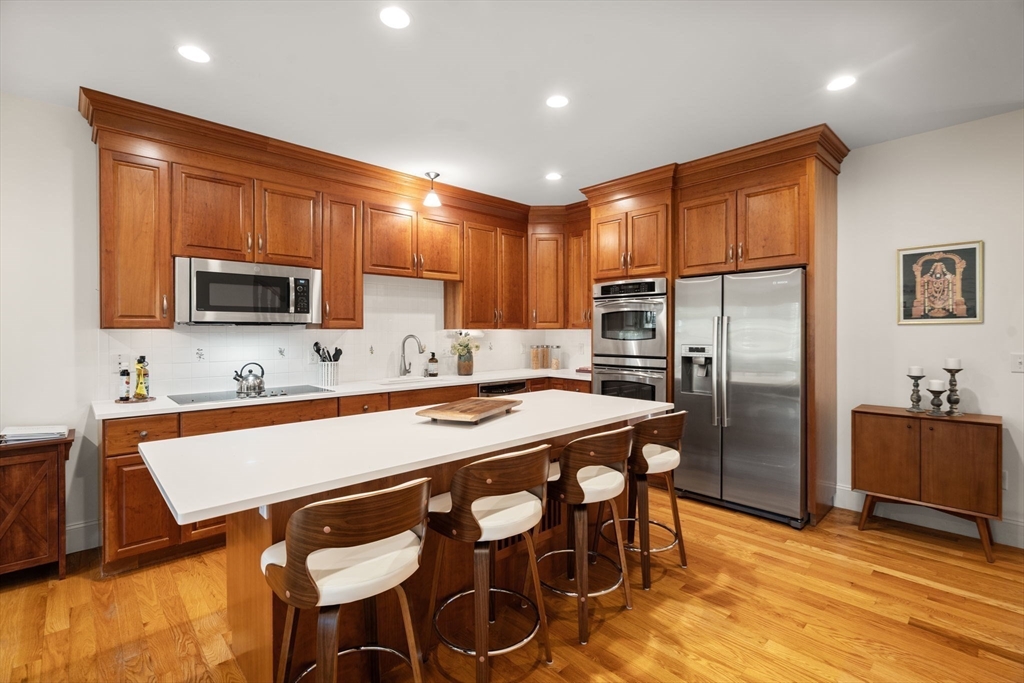 287 Langley Road, Unit 43 Newton, MA 02459 - Photo 11 of 36 a kitchen with stainless steel appliances granite countertop a refrigerator a stove a sink a dining table and chairs with wooden floor