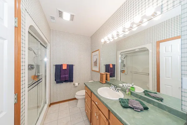 a spacious bathroom with a granite countertop sink a toilet a mirror and shower