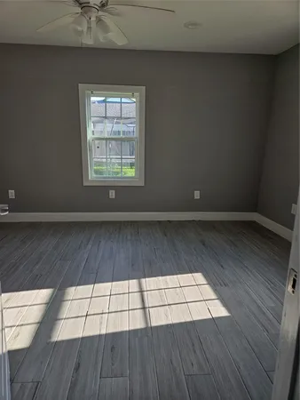 a view of empty room with wooden floor and fan