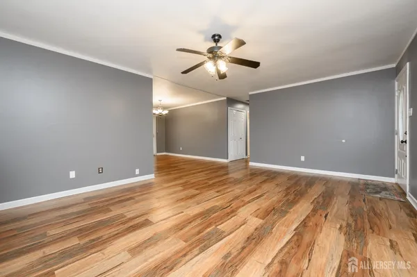 a view of an empty room with wooden floor and a ceiling fan