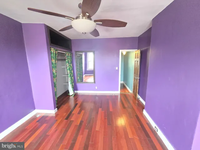 a view of an empty room with window and wooden floor