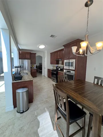 a kitchen with stainless steel appliances a table chairs microwave and stove