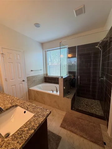 a bathroom with a granite countertop sink a mirror and shower