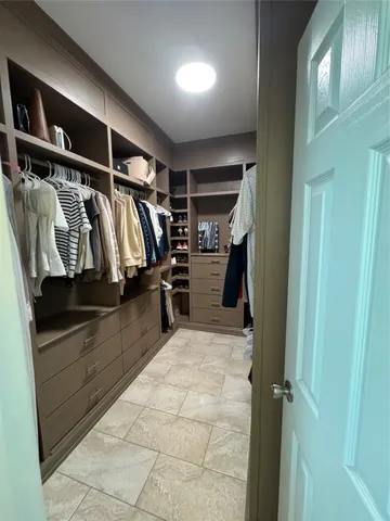 a view of walk in closet with clothes and shoes