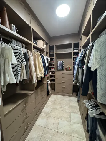 a view of walk in closet with clothes and shoes