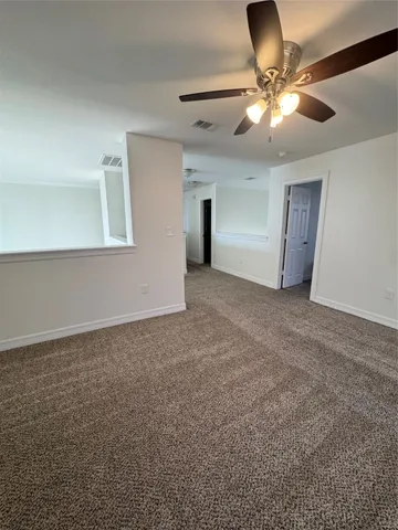 an empty room with a chandelier fan and windows