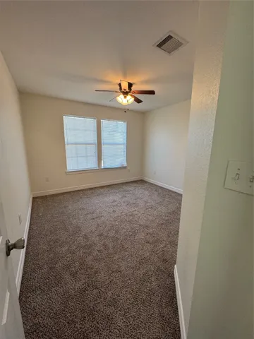 an empty room with windows and fan