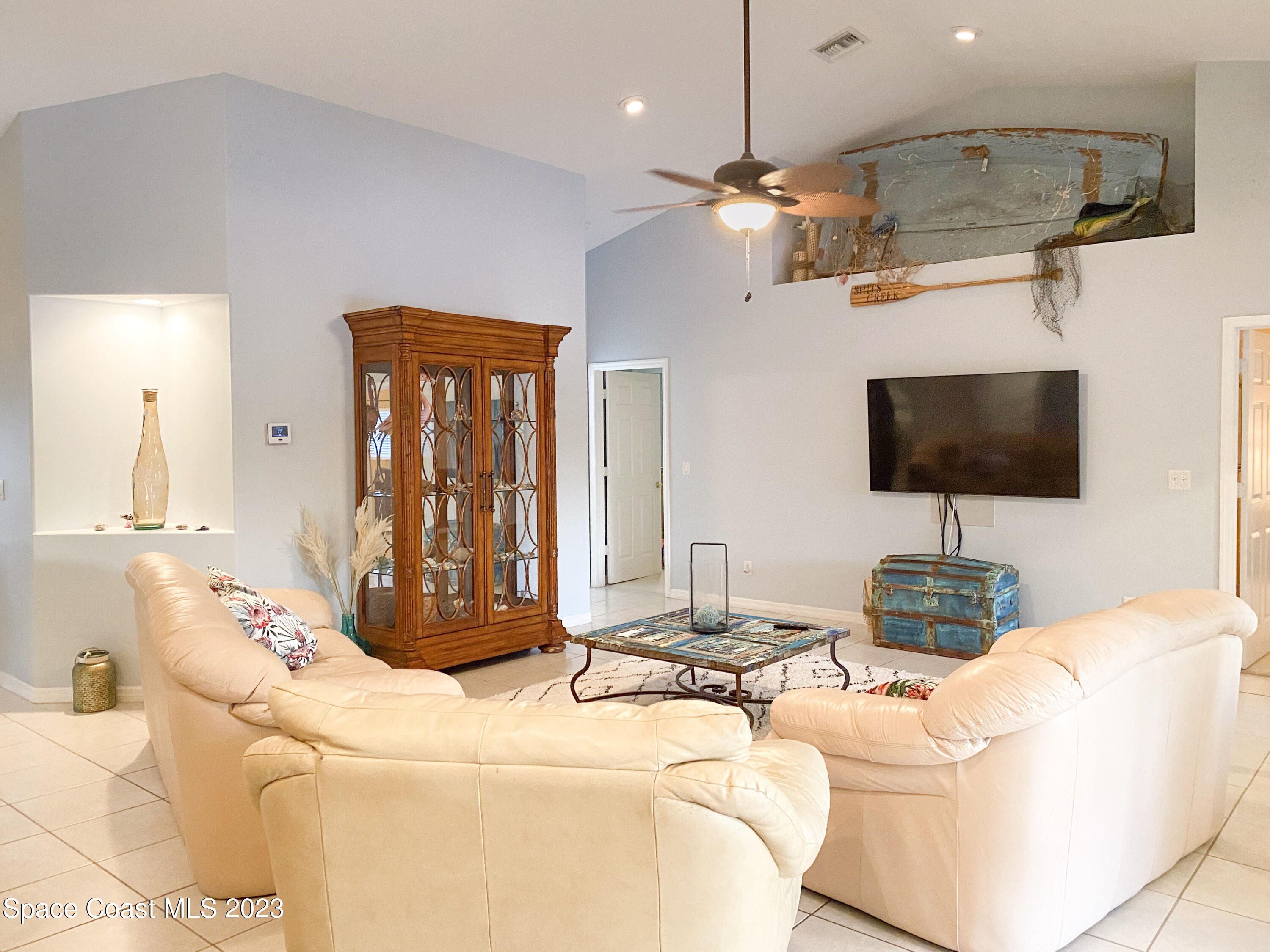 5080 Seiler Street Melbourne Beach, FL 32951 - Photo 12 of 34 a living room with a flat screen tv and a chandelier