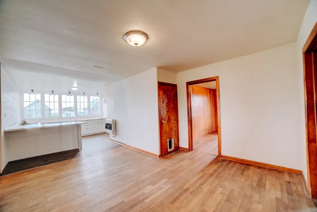 a view of an empty room with glass door and wooden floor