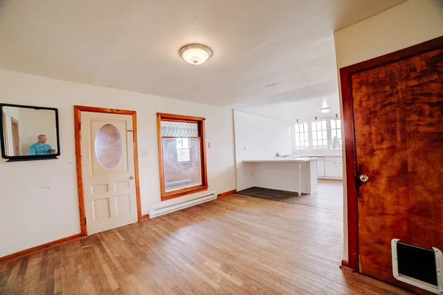 a view of an empty room with wooden floor and a window