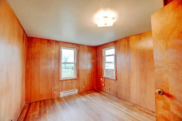 a view of empty room with wooden floor and window