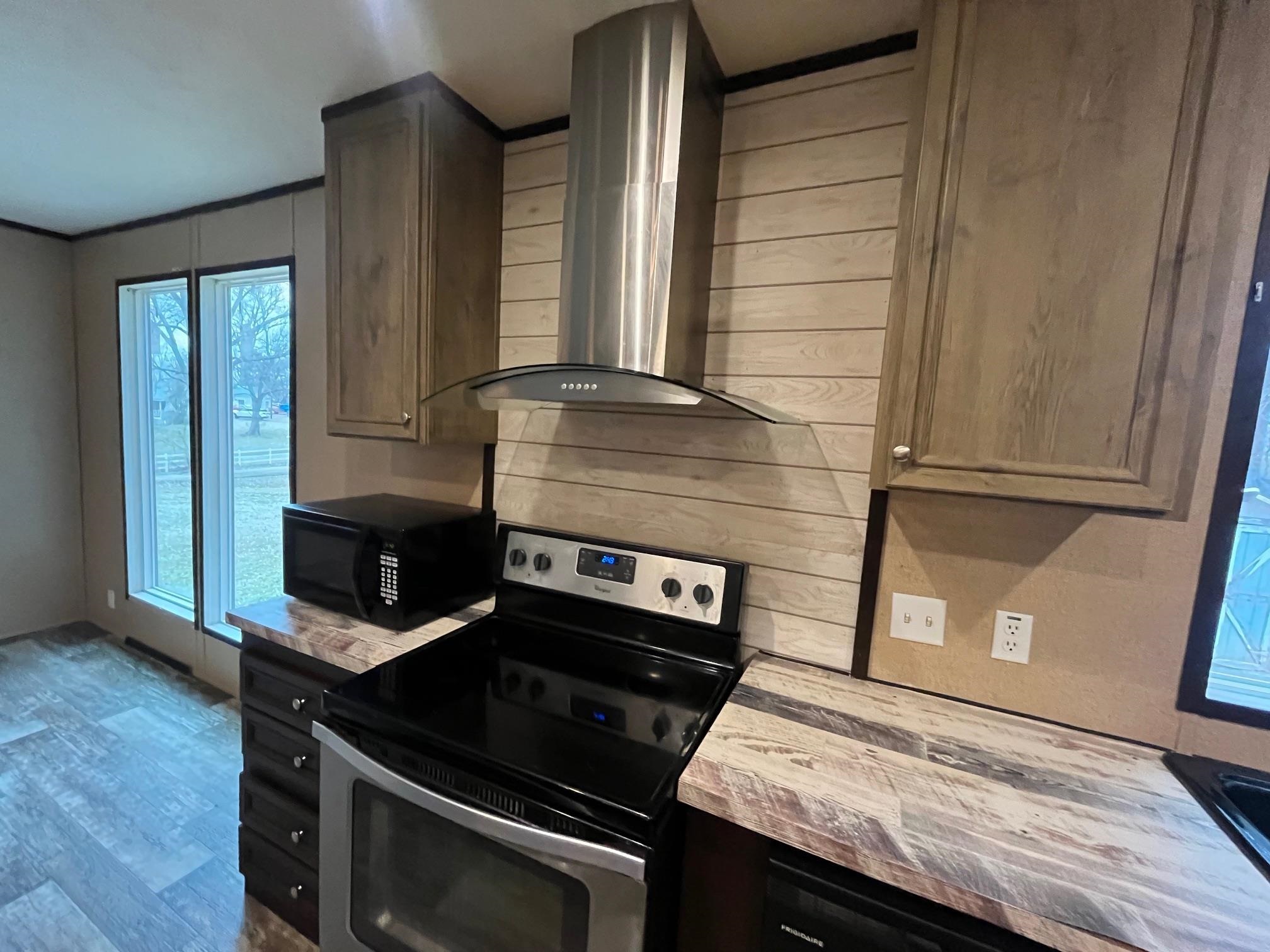 100 Stoots Road Brownsville, TN 38012 - Photo 6 of 18 Kitchen with stainless steel range with electric stovetop, hardwood / wood-style floors, and wall chimney range hood