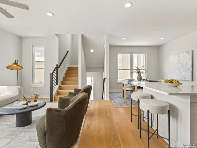 a living room with furniture a large window and wooden floor